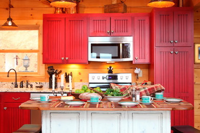 Example of a mountain style single-wall medium tone wood floor open concept kitchen design in Charlotte with stainless steel appliances and red cabinets