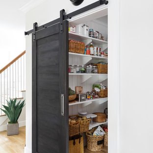 Mid-sized traditional kitchen pantry in Boston with open cabinets, white cabinets, light hardwood floors, a farmhouse sink, marble benchtops, stainless steel appliances and with island.