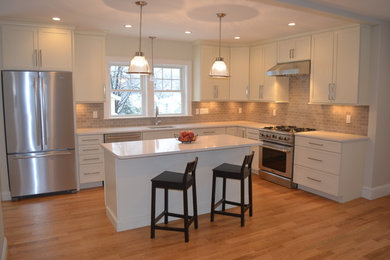 Inspiration for a timeless l-shaped eat-in kitchen remodel in Boston with an undermount sink, shaker cabinets, white cabinets, quartz countertops, gray backsplash, stone tile backsplash and stainless steel appliances