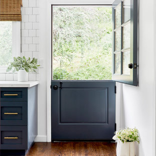 Photo of a mid-sized beach style galley separate kitchen in Los Angeles with a farmhouse sink, shaker cabinets, blue cabinets, quartz benchtops, white splashback, subway tile splashback, stainless steel appliances, dark hardwood floors, no island, brown floor and blue benchtop.