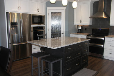 Eat-in kitchen - mid-sized transitional u-shaped dark wood floor and brown floor eat-in kitchen idea in Edmonton with an undermount sink, recessed-panel cabinets, white cabinets, granite countertops, gray backsplash, porcelain backsplash, stainless steel appliances and an island
