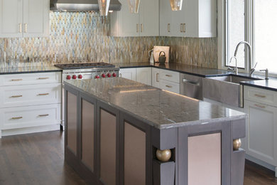 Inspiration for a large transitional l-shaped dark wood floor and brown floor kitchen pantry remodel in Kansas City with a farmhouse sink, shaker cabinets, white cabinets, metal backsplash, stainless steel appliances, an island and metallic backsplash