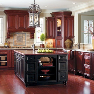 Foto di una grande cucina classica con ante con bugna sagomata, ante in legno bruno, top in quarzo composito, paraspruzzi in travertino, parquet scuro, pavimento rosso, lavello stile country e paraspruzzi multicolore