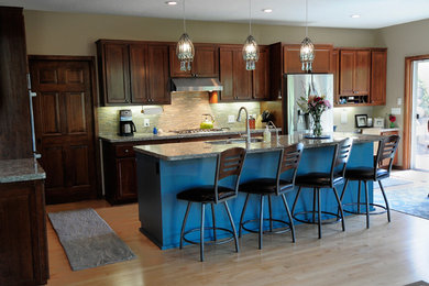 Inspiration for a large timeless l-shaped light wood floor eat-in kitchen remodel in Minneapolis with an undermount sink, dark wood cabinets, granite countertops, multicolored backsplash, stainless steel appliances and an island