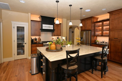 Example of a large classic l-shaped medium tone wood floor and brown floor eat-in kitchen design in Boise with a drop-in sink, flat-panel cabinets, medium tone wood cabinets, laminate countertops, beige backsplash, ceramic backsplash, stainless steel appliances, an island and beige countertops
