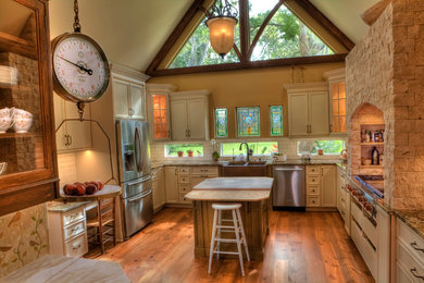 Example of a cottage medium tone wood floor eat-in kitchen design in Tampa with a farmhouse sink, flat-panel cabinets, white cabinets, granite countertops, white backsplash, subway tile backsplash, stainless steel appliances and an island