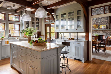 Kitchen - large rustic medium tone wood floor and brown floor kitchen idea in New York with a farmhouse sink, beaded inset cabinets, gray cabinets, granite countertops, white backsplash, glass tile backsplash, stainless steel appliances, an island and white countertops