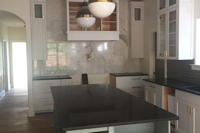 Immagine di un cucina con isola centrale tradizionale con ante in stile shaker, ante bianche, top in granito, paraspruzzi bianco e paraspruzzi in lastra di pietra