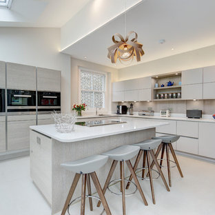 Photo of a large contemporary l-shaped kitchen in London with a submerged sink, flat-panel cabinets, grey cabinets, grey splashback, glass sheet splashback, black appliances and an island.