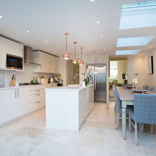 Photo of a medium sized modern single-wall kitchen/diner in London with a belfast sink, flat-panel cabinets, white cabinets, white splashback, stainless steel appliances, an island, beige floors and white worktops.