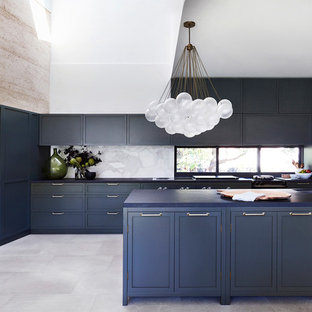 This is an example of a transitional l-shaped kitchen in Sydney with an undermount sink, shaker cabinets, blue cabinets, white splashback, window splashback, stainless steel appliances, with island, grey floor and blue benchtop.