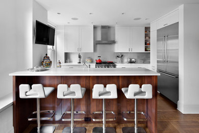 Inspiration for a mid-sized contemporary u-shaped light wood floor and brown floor open concept kitchen remodel in New York with recessed-panel cabinets, white cabinets, granite countertops, stainless steel appliances, an undermount sink, gray backsplash, stone slab backsplash and a peninsula