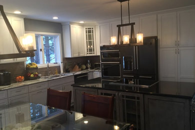 Mid-sized mountain style l-shaped dark wood floor eat-in kitchen photo in New York with an undermount sink, shaker cabinets, distressed cabinets, quartz countertops, gray backsplash, stone tile backsplash, black appliances and an island
