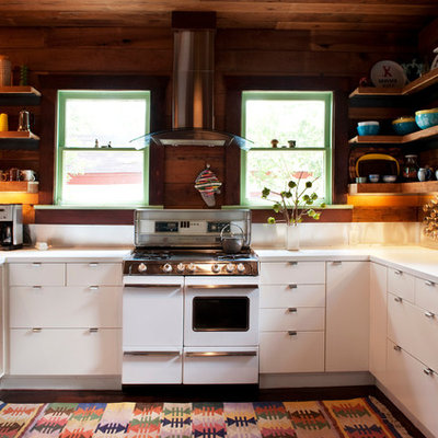 Inspiration for a mid-sized eclectic u-shaped dark wood floor eat-in kitchen remodel in Austin with a double-bowl sink, flat-panel cabinets, white cabinets, white backsplash, stainless steel appliances, laminate countertops and a peninsula