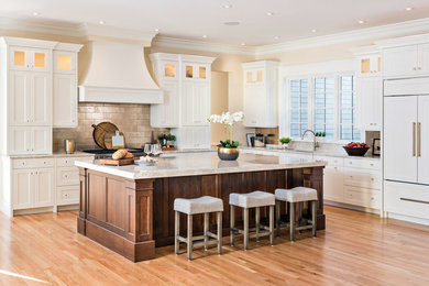 Inspiration for a large transitional l-shaped medium tone wood floor and brown floor enclosed kitchen remodel in Boston with an undermount sink, shaker cabinets, white cabinets, granite countertops, beige backsplash, subway tile backsplash, paneled appliances, an island and beige countertops