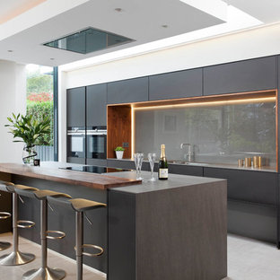 Immagine di una grande cucina moderna con ante lisce, ante nere, paraspruzzi grigio, paraspruzzi con lastra di vetro, elettrodomestici neri e pavimento grigio