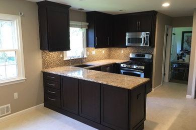 Example of a mid-sized trendy l-shaped travertine floor eat-in kitchen design in Newark with an undermount sink, shaker cabinets, dark wood cabinets, granite countertops, beige backsplash, mosaic tile backsplash, stainless steel appliances and a peninsula