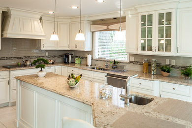 Huge trendy l-shaped porcelain tile eat-in kitchen photo in New York with an undermount sink, raised-panel cabinets, white cabinets, quartz countertops, multicolored backsplash, glass tile backsplash, white appliances and an island