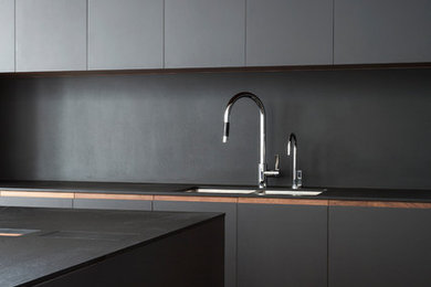 Foto di una cucina design di medie dimensioni con lavello a doppia vasca, ante lisce, ante nere, paraspruzzi nero, pavimento in legno massello medio e pavimento marrone