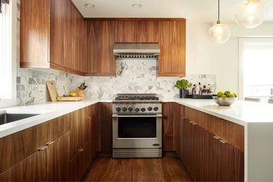 Inspiration for a modern medium tone wood floor kitchen remodel in Seattle with an undermount sink, flat-panel cabinets, medium tone wood cabinets, quartzite countertops, white backsplash, stone tile backsplash, stainless steel appliances and a peninsula