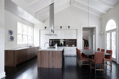 Immagine di una cucina contemporanea di medie dimensioni con lavello sottopiano, ante lisce, ante in legno bruno, elettrodomestici neri e parquet scuro