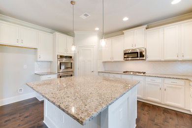 Mid-sized transitional u-shaped dark wood floor and brown floor open concept kitchen photo in Other with an undermount sink, recessed-panel cabinets, white cabinets, granite countertops, white backsplash, subway tile backsplash, stainless steel appliances and an island