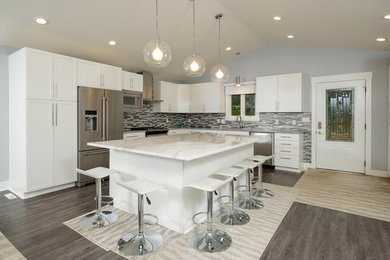 Inspiration for a contemporary l-shaped vinyl floor and gray floor open concept kitchen remodel in Other with an undermount sink, flat-panel cabinets, white cabinets, quartz countertops, gray backsplash, stainless steel appliances, an island and white countertops