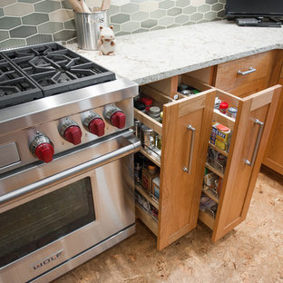 Modelo de cocina en L, minimalista, de tamaño medio, con despensa, fregadero bajoencimera, armarios con paneles empotrados, puertas de armario de madera clara, salpicadero multicolor, salpicadero de azulejos tipo metro, electrodomésticos de acero inoxidable, suelo de corcho y una isla