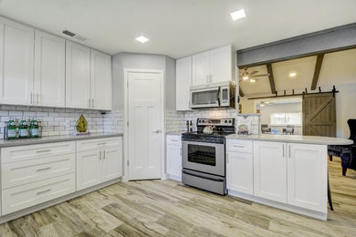 Inspiration for a mid-sized u-shaped ceramic tile and gray floor eat-in kitchen remodel in Austin with flat-panel cabinets, white cabinets, quartz countertops, white backsplash, cement tile backsplash, stainless steel appliances and gray countertops