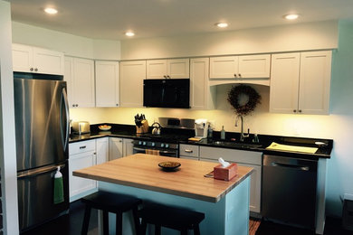 グランドラピッズにある広いコンテンポラリースタイルのおしゃれなキッチン (ダブルシンク、落し込みパネル扉のキャビネット、白いキャビネット、シルバーの調理設備) の写真