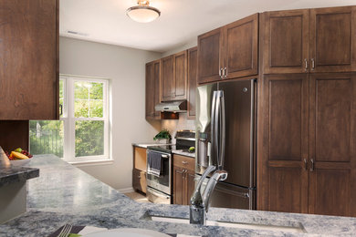 Eat-in kitchen - mid-sized transitional galley light wood floor and brown floor eat-in kitchen idea in Milwaukee with an undermount sink, dark wood cabinets, white backsplash, subway tile backsplash, stainless steel appliances, a peninsula, shaker cabinets and quartzite countertops