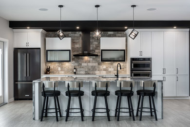 Example of a mid-sized trendy galley laminate floor and gray floor eat-in kitchen design in Other with an undermount sink, shaker cabinets, white cabinets, granite countertops, gray backsplash, travertine backsplash, black appliances, an island and gray countertops