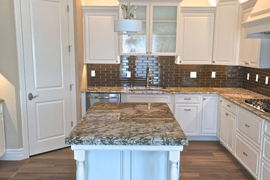 Inredning av ett klassiskt mellanstort kök, med en undermonterad diskho, luckor med upphöjd panel, vita skåp, brunt stänkskydd, stänkskydd i keramik, rostfria vitvaror och en köksö
