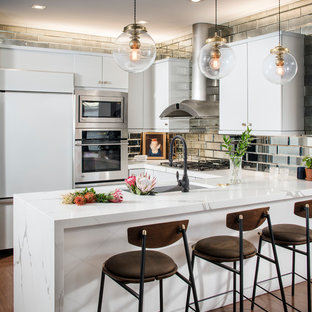 Mid-sized eclectic u-shaped medium tone wood floor and brown floor kitchen photo in San Francisco with flat-panel cabinets, white cabinets, quartz countertops, metallic backsplash, mirror backsplash, a peninsula, an undermount sink, white appliances and white countertops