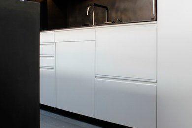 ニューヨークにある北欧スタイルのおしゃれなI型キッチン (フラットパネル扉のキャビネット、白いキャビネット、茶色いキッチンパネル、濃色無垢フローリング、グレーの床) の写真