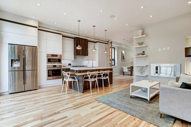 Inspiration for a mid-sized contemporary single-wall light wood floor open concept kitchen remodel in Toronto with an undermount sink, flat-panel cabinets, white cabinets, quartzite countertops, white backsplash, ceramic backsplash, stainless steel appliances and an island