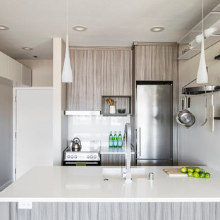 Diseño de cocina comedor de galera, minimalista, pequeña, sin isla, con fregadero bajoencimera, armarios con paneles lisos, puertas de armario marrones, encimera de cuarcita, salpicadero blanco, electrodomésticos de acero inoxidable y suelo de corcho