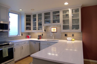 Transitional eat-in kitchen photo in Seattle with an undermount sink, raised-panel cabinets, white cabinets, solid surface countertops, gray backsplash, glass tile backsplash, stainless steel appliances and no island