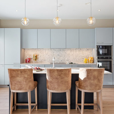 Inspiration for a large contemporary galley light wood floor and beige floor kitchen remodel in Dublin with an undermount sink, flat-panel cabinets, blue cabinets, gray backsplash, stainless steel appliances, an island and gray countertops
