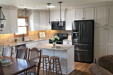 Inspiration for a mid-sized transitional l-shaped medium tone wood floor eat-in kitchen remodel in Other with a double-bowl sink, shaker cabinets, white cabinets, granite countertops, beige backsplash, stone tile backsplash, black appliances and an island
