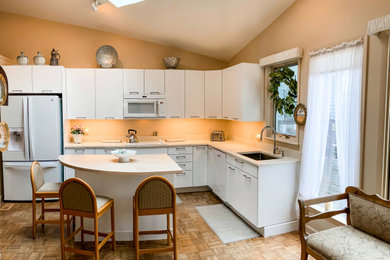 ワシントンD.C.にある高級な中くらいなトランジショナルスタイルのおしゃれなキッチン (シングルシンク、フラットパネル扉のキャビネット、白いキャビネット、大理石カウンター、ベージュキッチンパネル、大理石のキッチンパネル、白い調理設備、無垢フローリング、茶色い床、ベージュのキッチンカウンター、三角天井) の写真