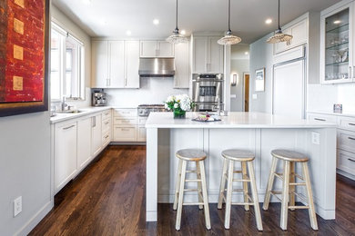Large trendy u-shaped dark wood floor and brown floor open concept kitchen photo in Seattle with an undermount sink, shaker cabinets, white cabinets, quartz countertops, white backsplash, porcelain backsplash, paneled appliances and an island