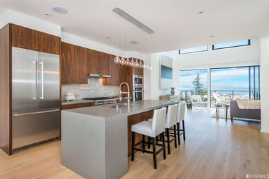 Eat-in kitchen - mid-sized contemporary medium tone wood floor eat-in kitchen idea in San Francisco with a single-bowl sink, flat-panel cabinets, quartz countertops, marble backsplash, stainless steel appliances and an island