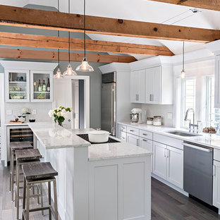 Idee per una grande cucina lineare stile marinaro con lavello sottopiano, ante in stile shaker, ante bianche, elettrodomestici in acciaio inossidabile, parquet chiaro, isola e pavimento marrone