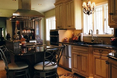 Mid-sized tuscan l-shaped kitchen photo in Other with raised-panel cabinets, granite countertops, stainless steel appliances and an island