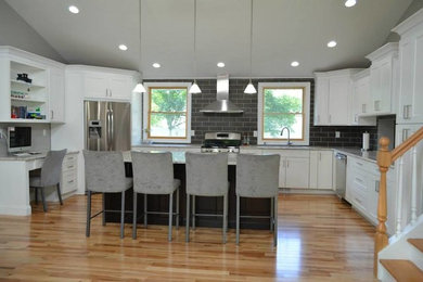 Example of a transitional light wood floor kitchen design in New York with recessed-panel cabinets, white cabinets and an island