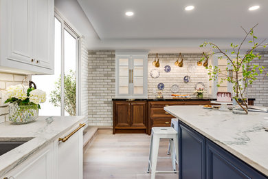 Inspiration for a french country u-shaped light wood floor and beige floor kitchen remodel in Calgary with an undermount sink, recessed-panel cabinets, blue cabinets, quartzite countertops, brick backsplash, paneled appliances, an island and beige countertops