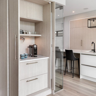 Diseño de cocina contemporánea con armarios con paneles lisos, puertas de armario de madera clara, suelo de madera clara, suelo beige y encimeras blancas