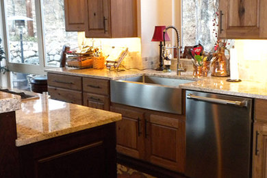 Example of a mid-sized classic l-shaped medium tone wood floor eat-in kitchen design in Denver with a farmhouse sink, raised-panel cabinets, light wood cabinets, granite countertops, beige backsplash, stone tile backsplash, stainless steel appliances and an island