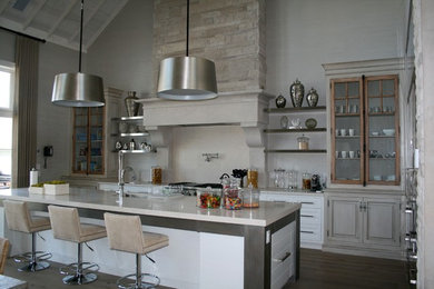 Foto de cocina rural con electrodomésticos de acero inoxidable, encimeras beige y pared de piedra